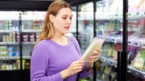 Woman in a supermarket holding packaged cheese  